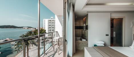 A modern balcony with a view of the sea and buildings.