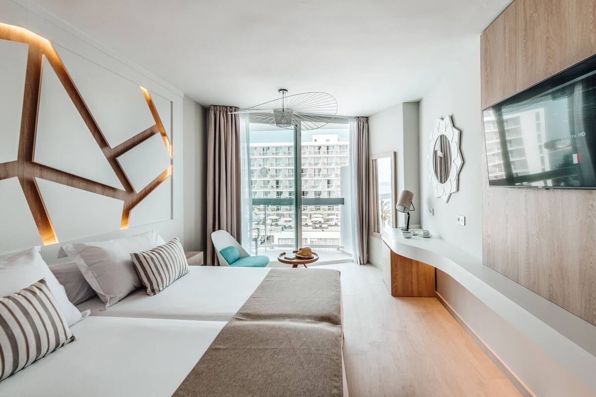 Une chambre d’hôtel moderne avec un grand lit, un canapé, une petite table et un téléviseur.