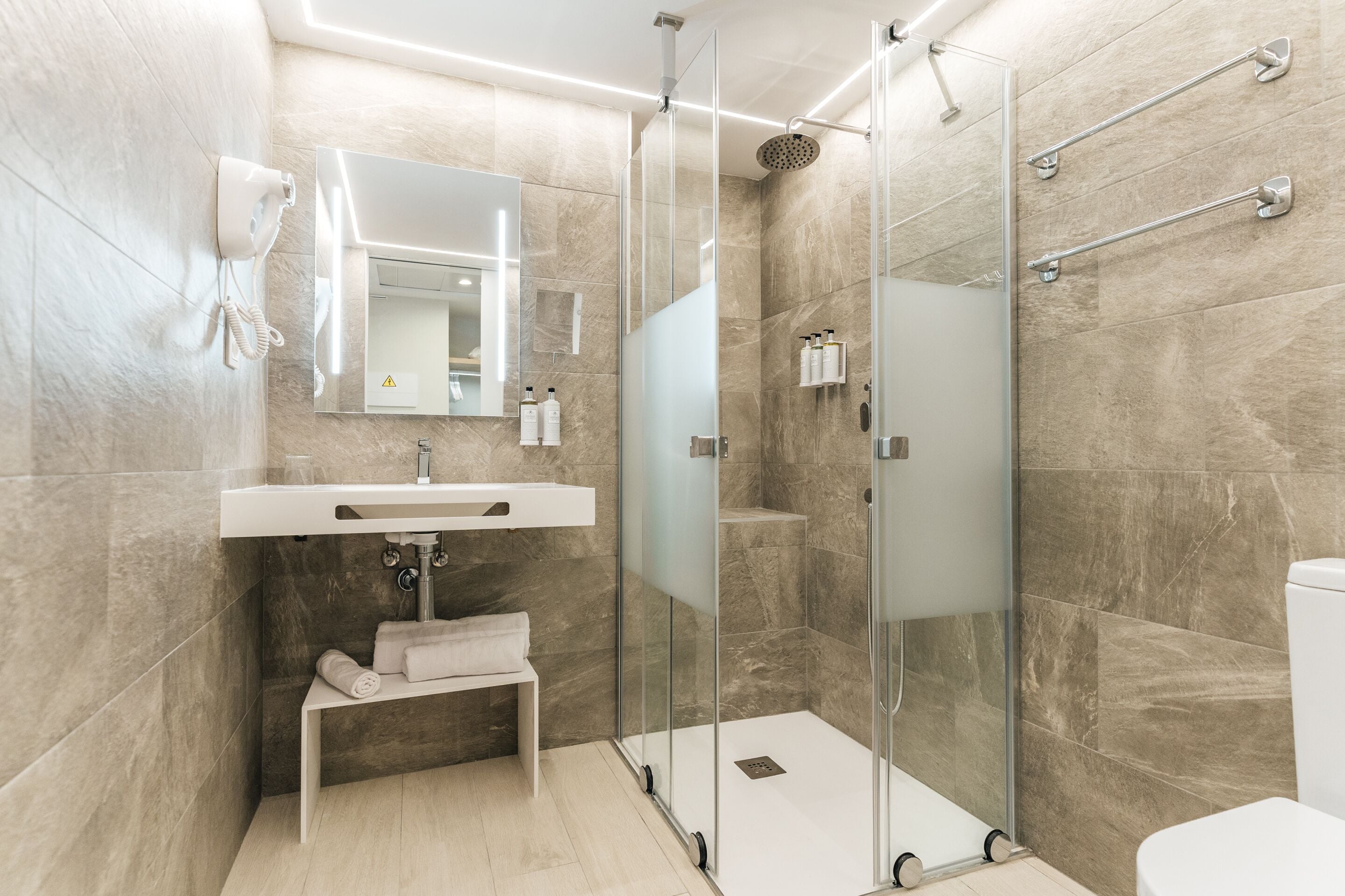 Un baño moderno con cabina de ducha de vidrio, un lavabo blanco y un espejo encima.