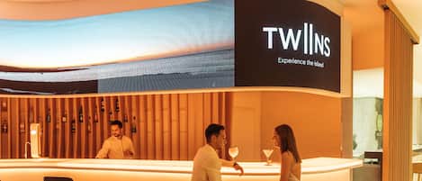 A TWINS lounge bar with a modern design, featuring a curved counter and bar stools.