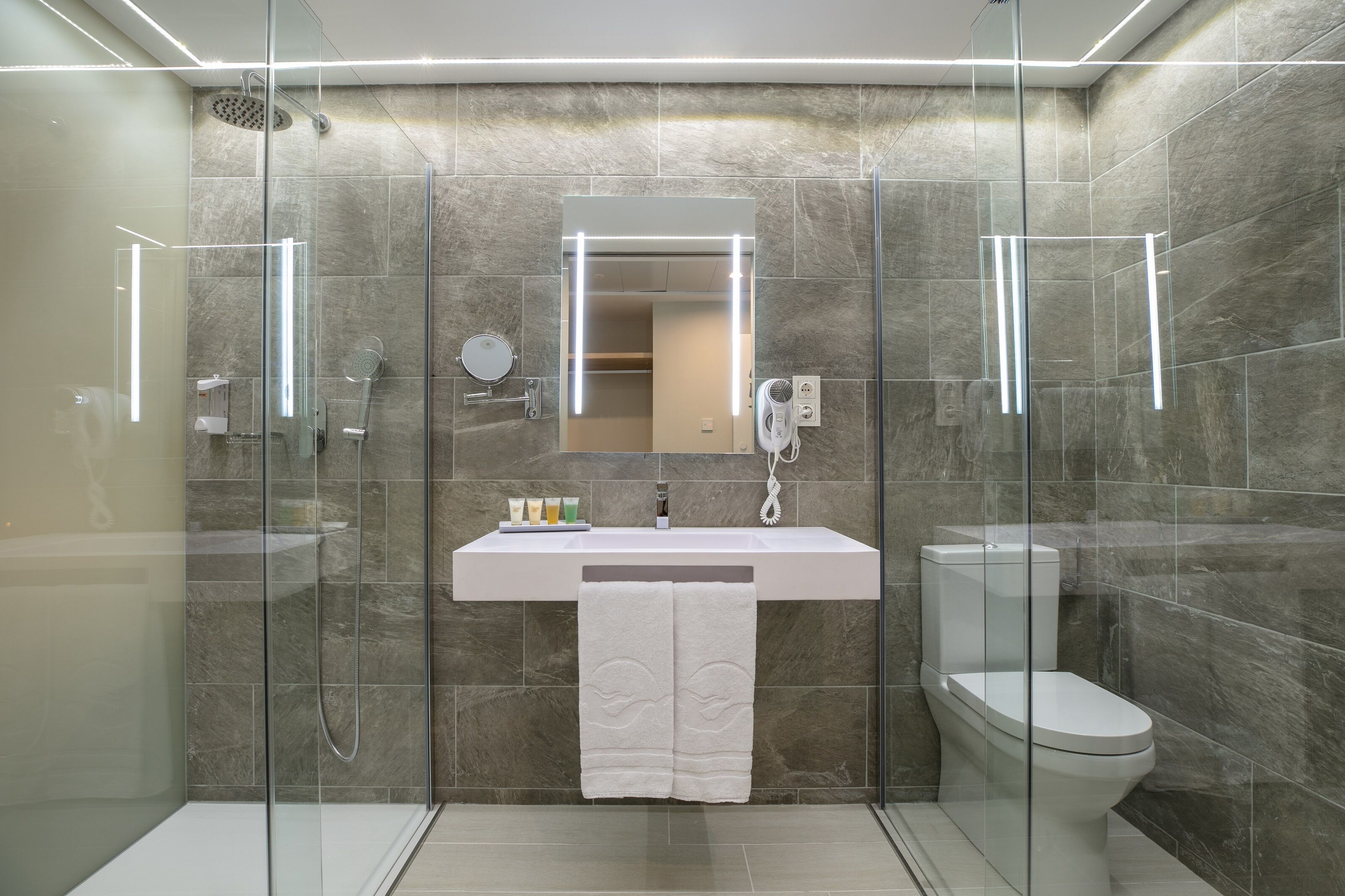 A modern bathroom with a glass-enclosed shower, a white sink, and a toilet.