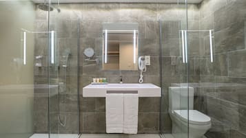 A modern bathroom with a glass-enclosed shower, a white sink, and a toilet.