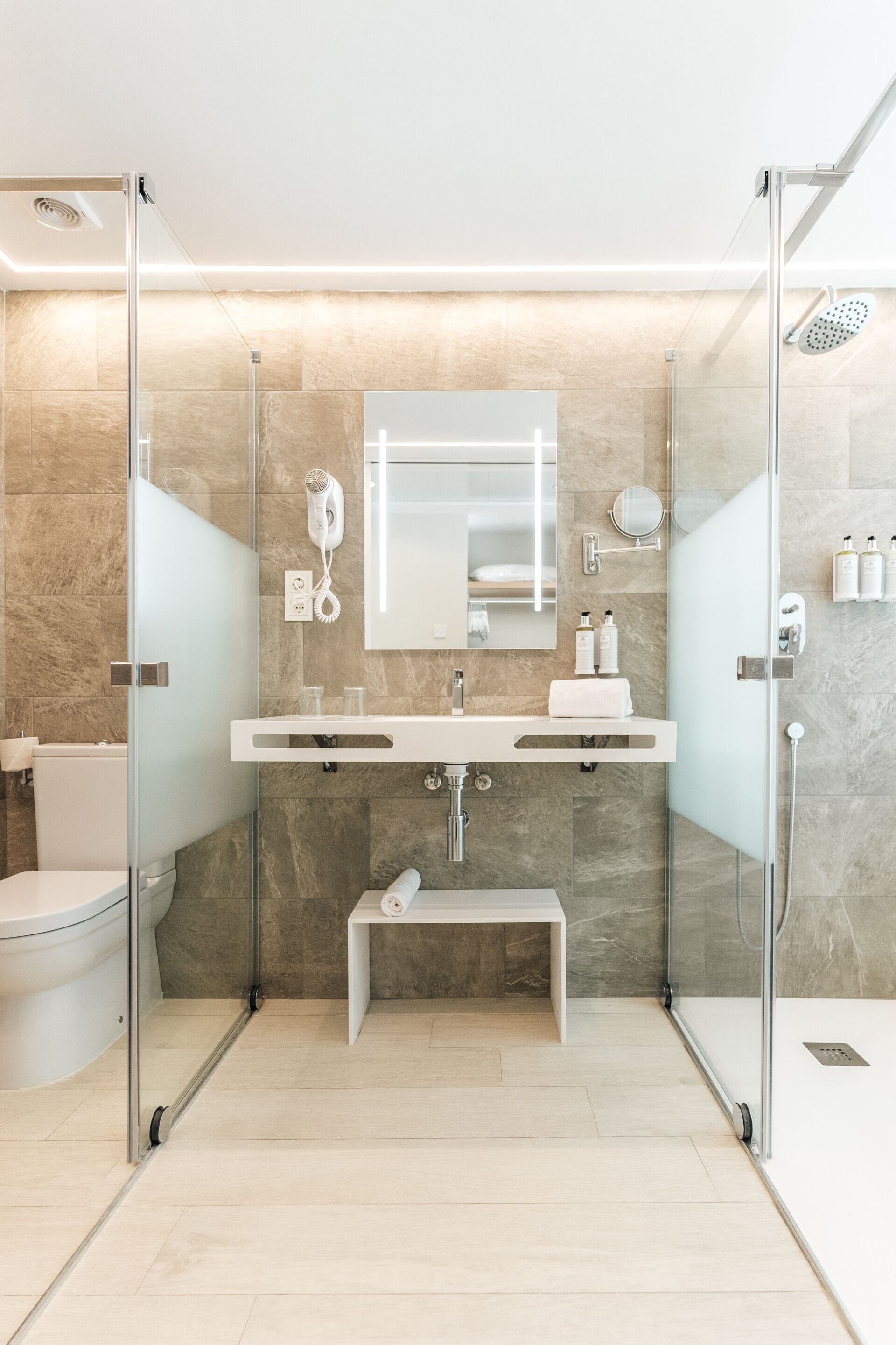 A modern bathroom with a glass-enclosed shower, a white sink, and a mirror above it.