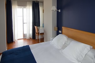 Una habitación de hotel con una cama, un escritorio y una silla.