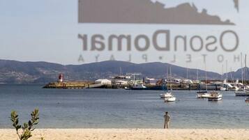 Cena costeira com praia, barcos e um farol.
