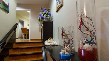 Una escalera conduce a un área de comedor con un florero de flores moradas en el rellano.