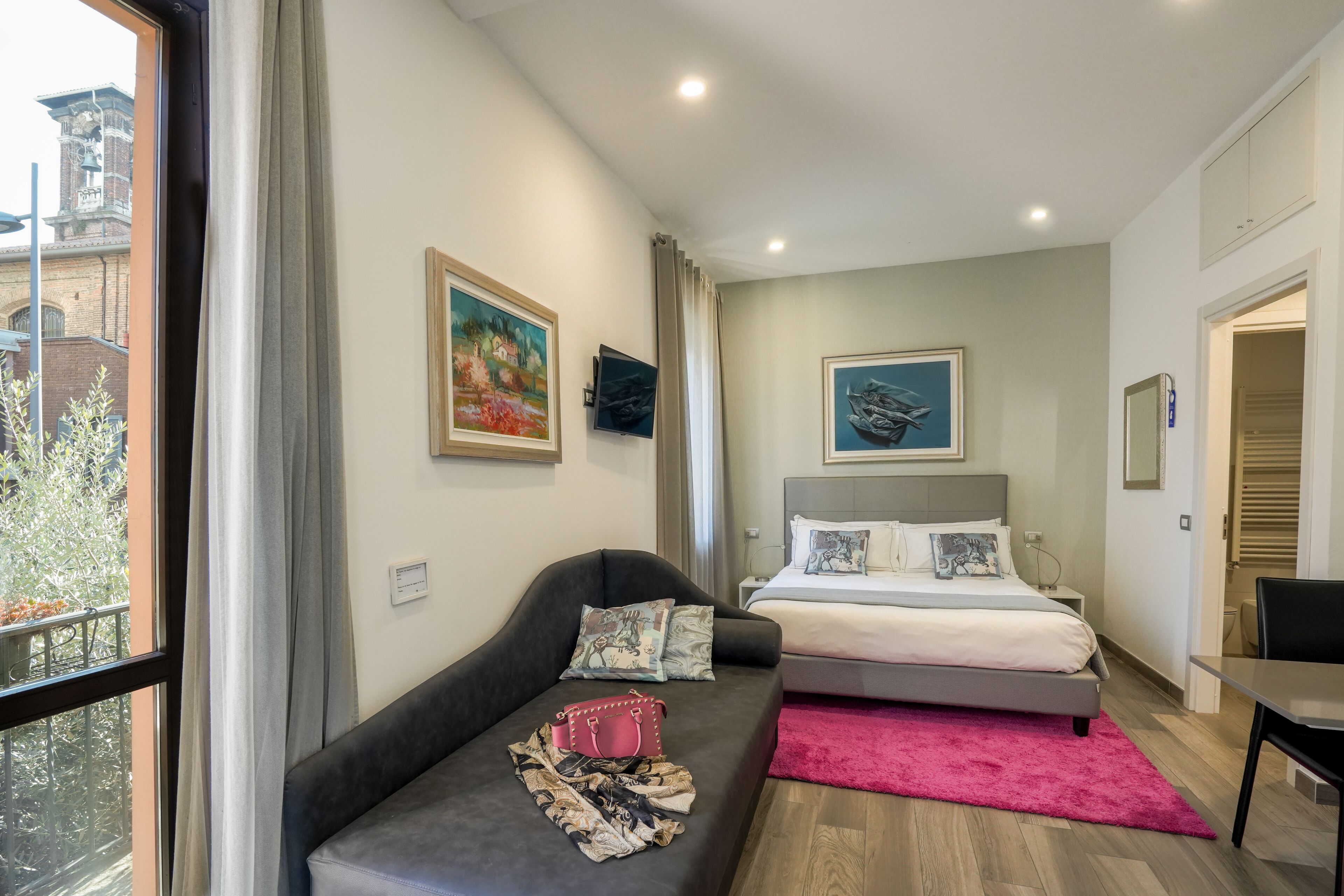 Un dormitorio moderno con cama, sofá y vista a un edificio.