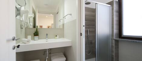 A modern bathroom with a white vanity, a glass shower enclosure, and a large mirror.