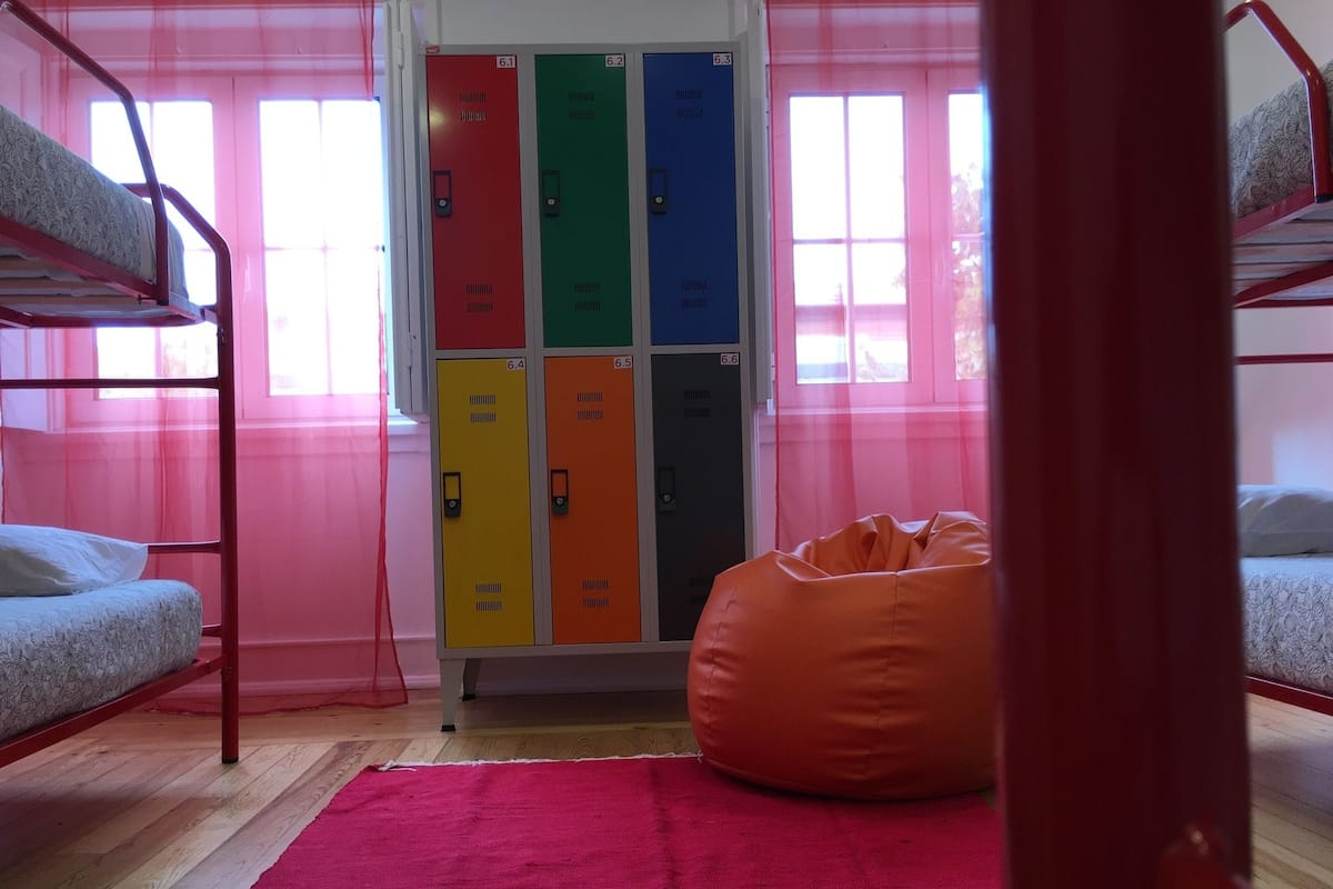 A dormitory room with bunk beds, a bean bag chair, and lockers.