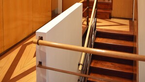 A hotel corridor with wooden paneling, a handrail, and a mirrored wall reflecting the staircase. - Terrace Lisbon Hostel (Lisbon)