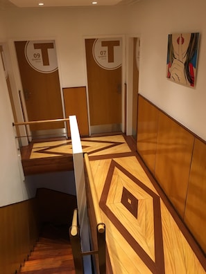 Ein Hotelzimmer mit einem geometrisch gemusterten Boden, zwei Türen mit den Beschriftungen '09' und '07' für die Zimmer 9 und 7 sowie einem Bild an der Wand.