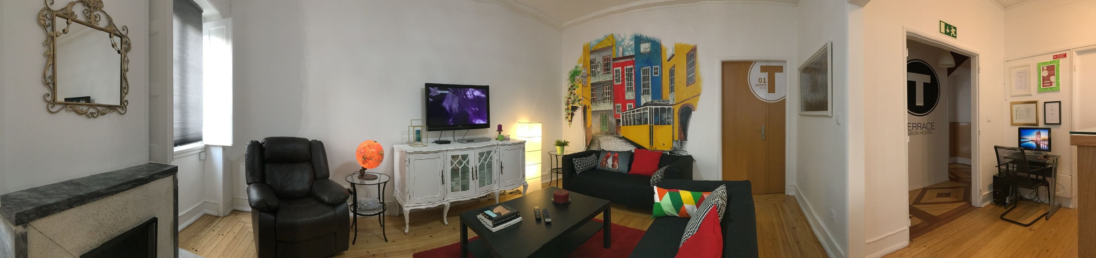 Olohuone, jossa on televisio, maapallo, sohva ja työpöytä, jossa on tietokone.