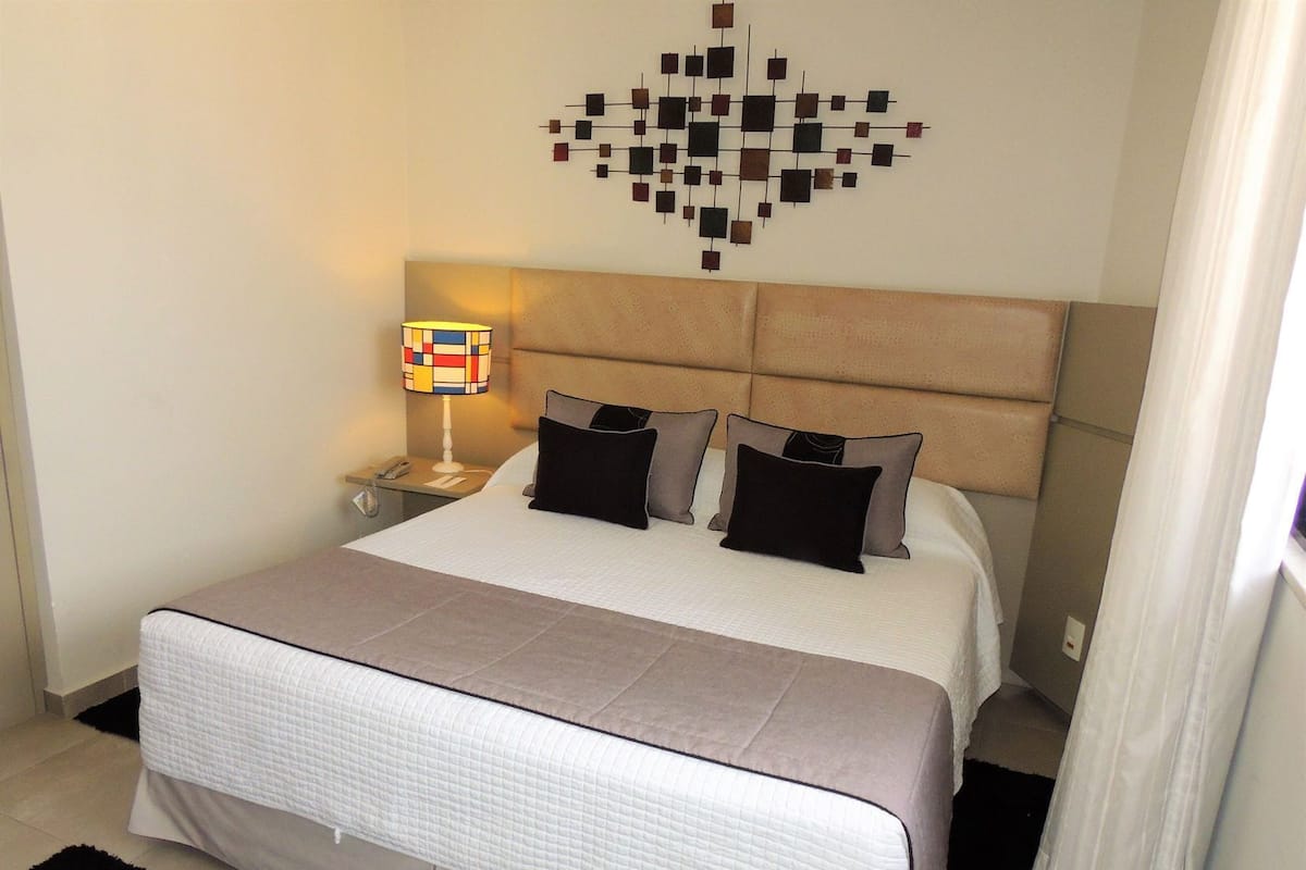 Habitación de hotel con una cama grande, una mesita de noche, una lámpara y una obra de arte en la pared.