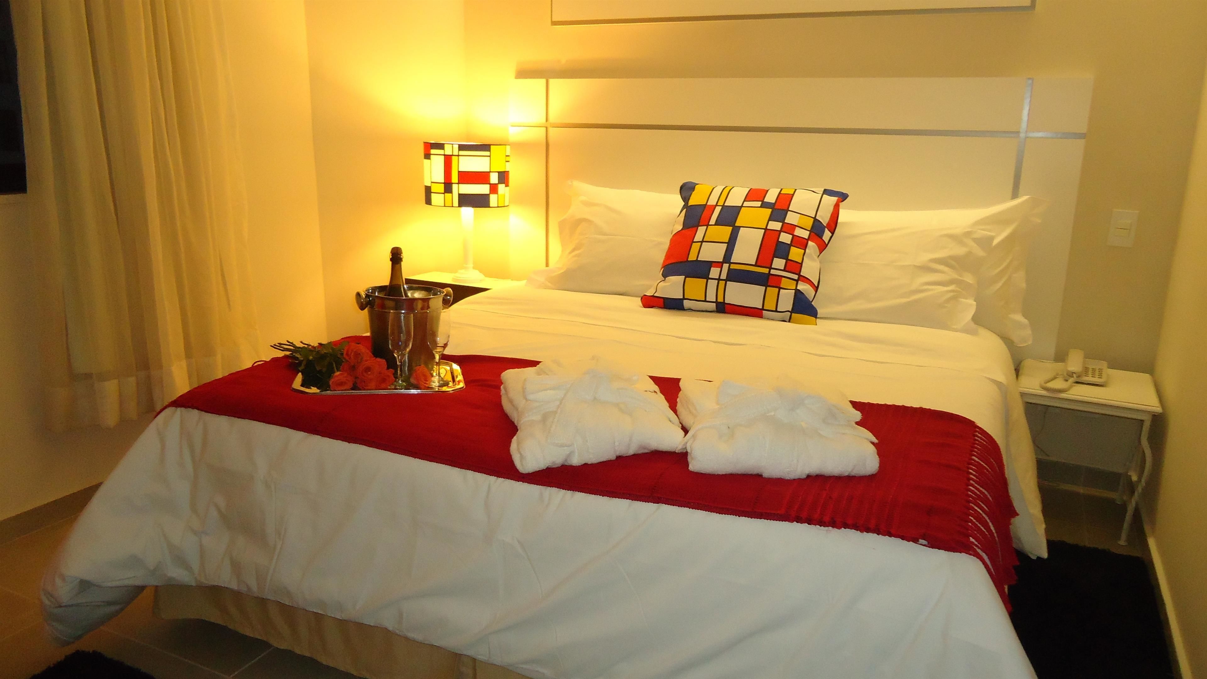 Una habitación de hotel con una cama bien hecha, una botella de champán y dos toallas sobre la cama.