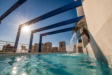 Una piscina al aire libre, sillones reclinables de piscina