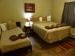 A hotel room with two beds, a nightstand with a lamp, and a painting on the wall. - Bent Prop Inn & Hostel Downtown (Anchorage)