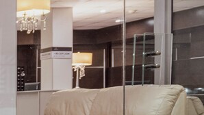A reception area with a beige sofa, a chandelier, and a reception desk. - Hotel Royal Colonia (Colonia del Sacramento)