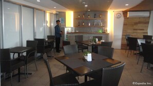 A restaurant with a modern interior, featuring a mix of dining tables and chairs, a bar area with shelves of bottles, and a clock on the wall. - Cebu R Hotel Mabolo (Cebu City)