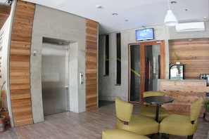 Un interno moderno con una reception, una televisione e una zona salotto con poltrone.