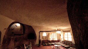 A cozy interior with a stone wall, a round table, and a sofa set. - Fairy Chimney Inn (Nevsehir)