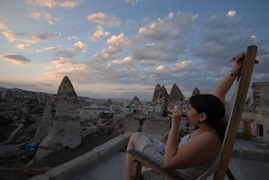 A person sitting on a bench overlooking a landscape with unique rock formations and traditional buildings.