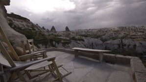 A terrace with stone benches and a table, overlooking a rocky landscape with unique geological formations. - Fairy Chimney Inn (Nevsehir)