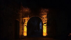 An arched stone entrance with illuminated walls and a cobblestone path leading through it. - Fairy Chimney Inn (Nevsehir)