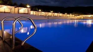 A swimming pool with metal railings at night, surrounded by buildings with lights. - Orient Hotel & Resort (Pyeongchang)