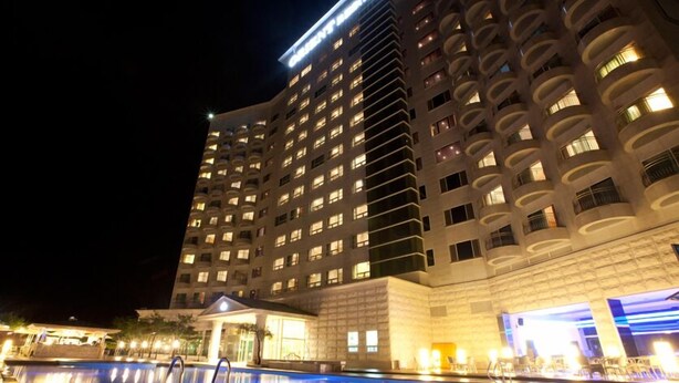 A high-rise hotel with multiple balconies, a swimming pool, and a well-lit entrance. - Orient Hotel & Resort (Pyeongchang)
