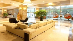 A modern lobby with a sofa, chairs, a large lamp, and a reception desk. - Orient Hotel & Resort (Pyeongchang)