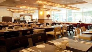 A spacious restaurant with high ceilings and modern chandeliers. Tables are neatly arranged with chairs, and the room has large windows allowing natural light. - Orient Hotel & Resort (Pyeongchang)