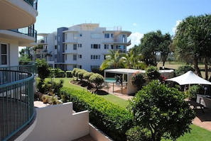A multi-story residential building with balconies, a swimming pool, and well-maintained gardens.