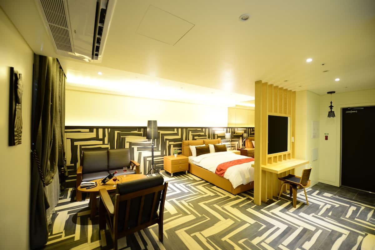 A hotel room with a bed, desk, chair, and a television.