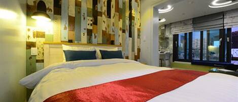 A hotel room with a large bed, a city view through the window, and a modern wall design.