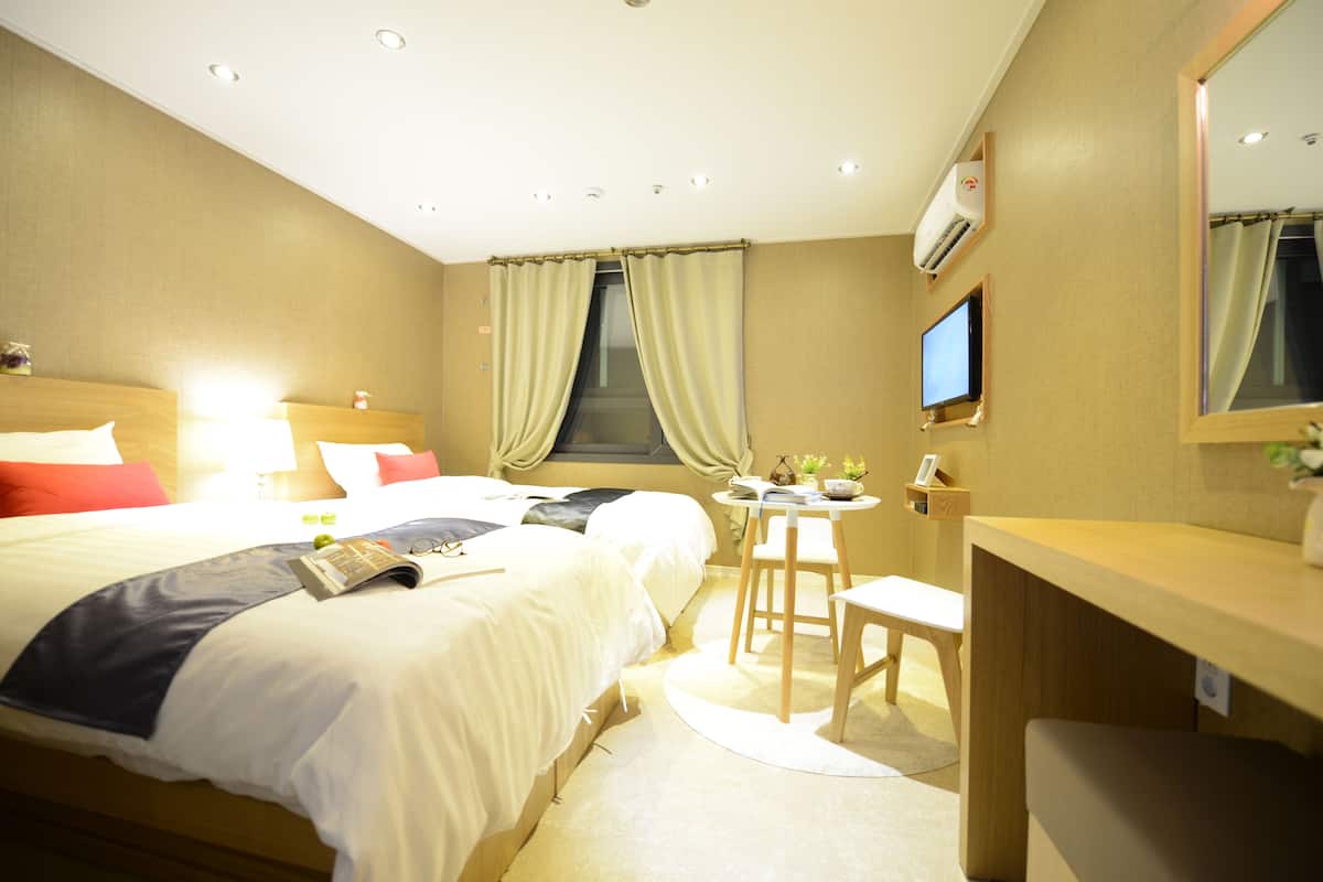 A hotel room with a large bed, bedside tables, a desk, and a TV.