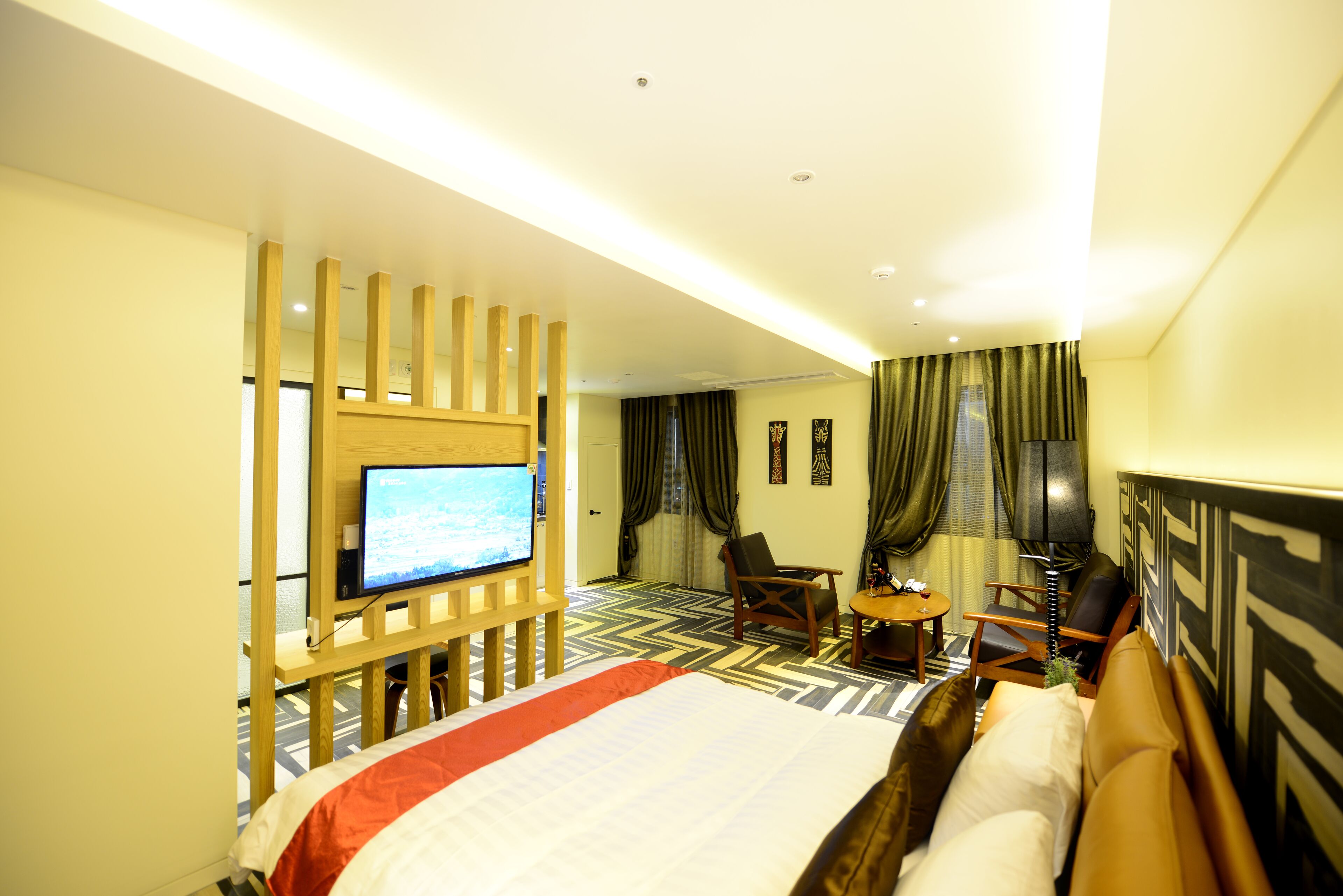 A hotel room with a large bed, a TV, a desk with a chair, and a small table.