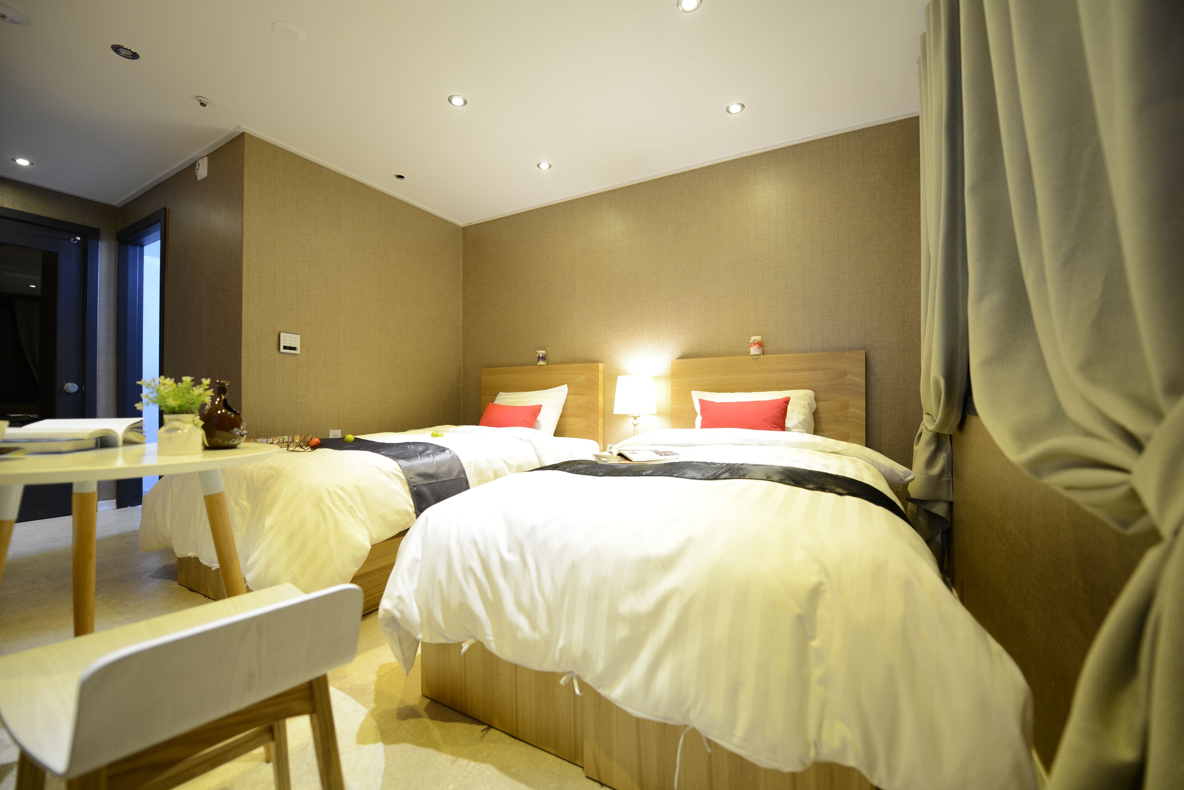 A hotel room with two beds, a table, and a chair.