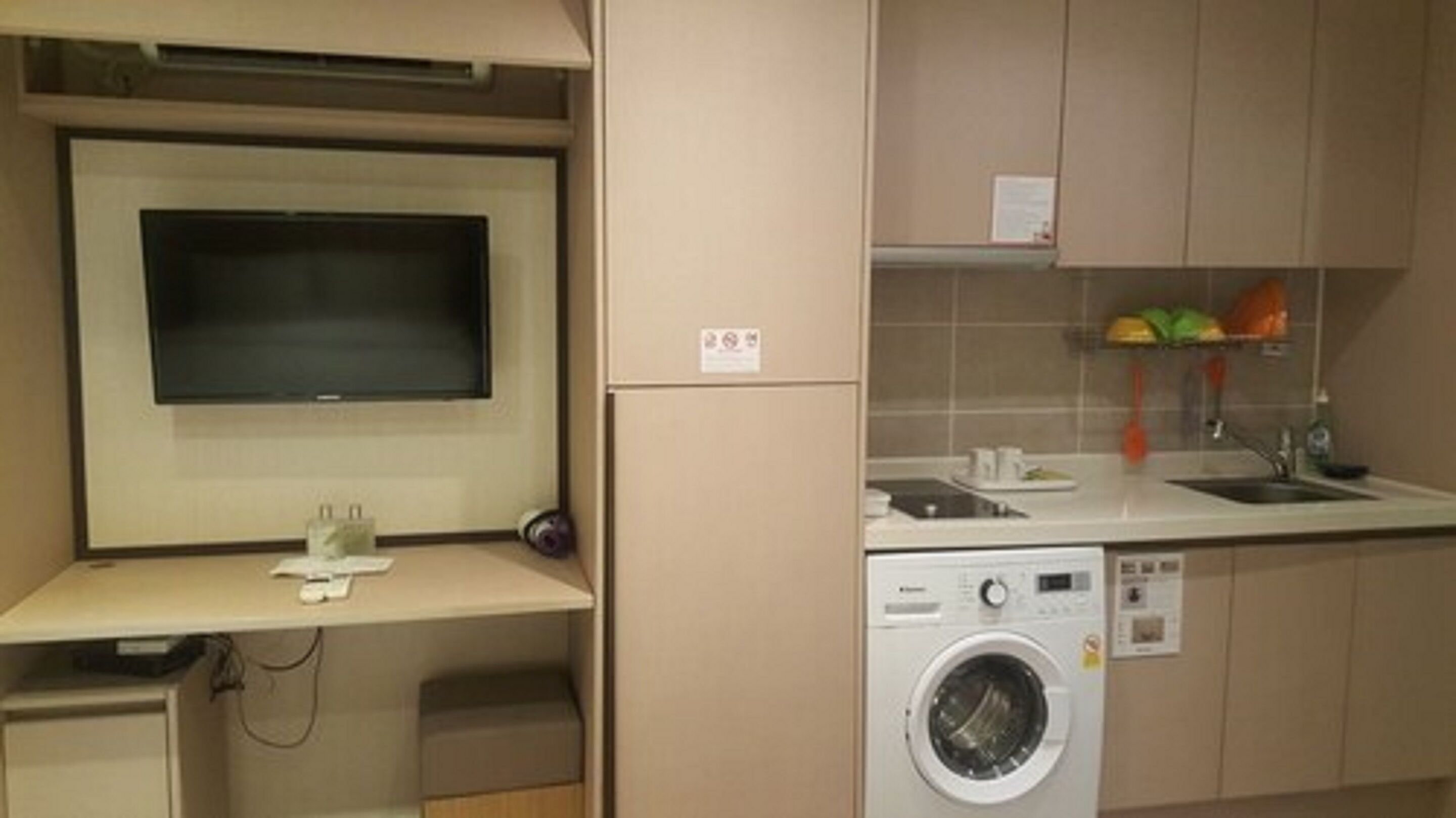 A compact kitchen with a built-in washing machine, a small sink, and a microwave.