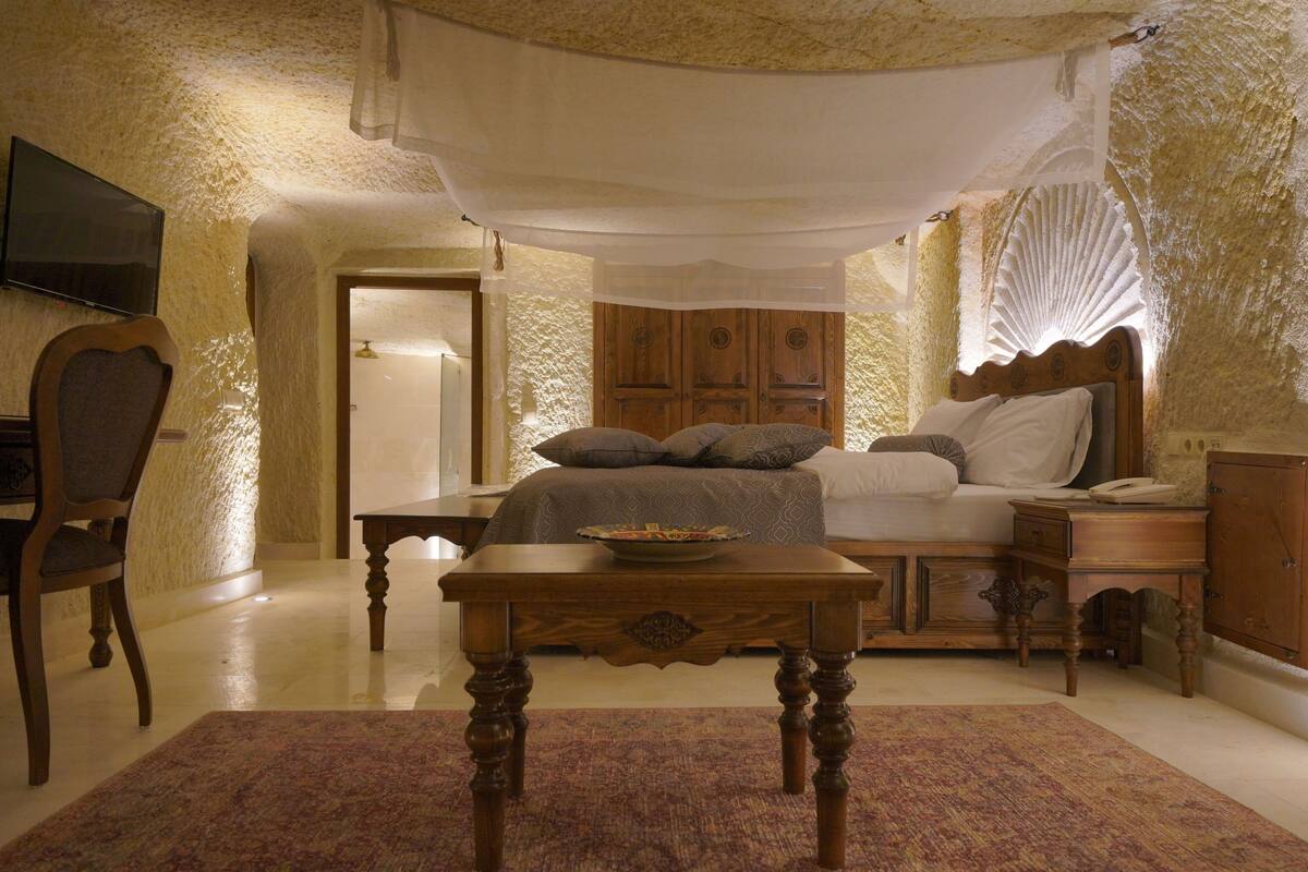 A bedroom with a bed, bedside table, and a television on the wall.