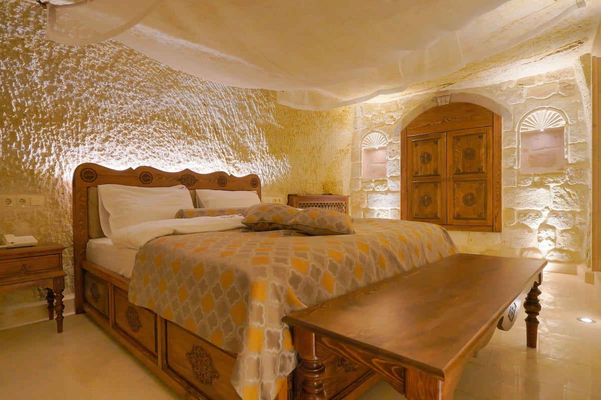 A bedroom with a large bed, wooden headboard, and a nightstand.