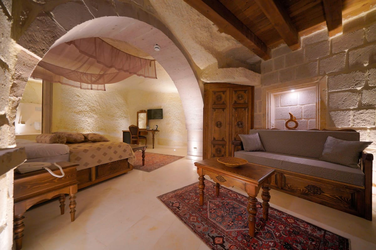 A cozy room with a bed, a wooden bench, a sofa, and a table.
