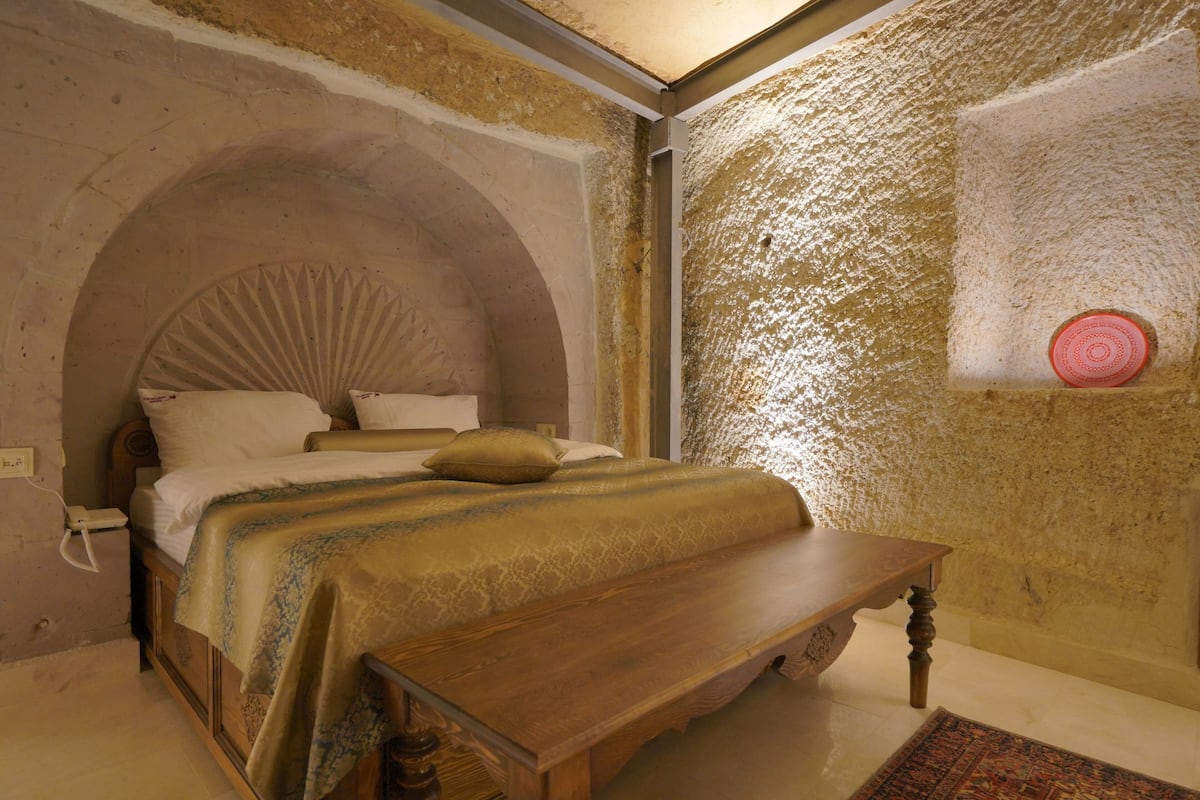 A bedroom with a wooden bed, a bench, and a textured wall.