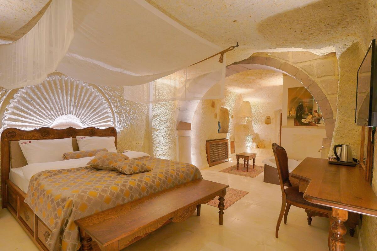 A bedroom with a bed, bench, dining table, and chairs.