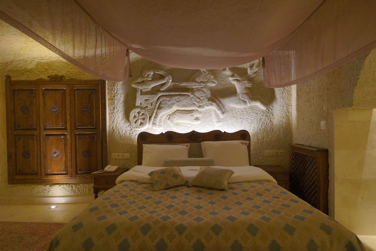 A bedroom with a bed, a wooden wardrobe, and a wall-mounted sculpture.