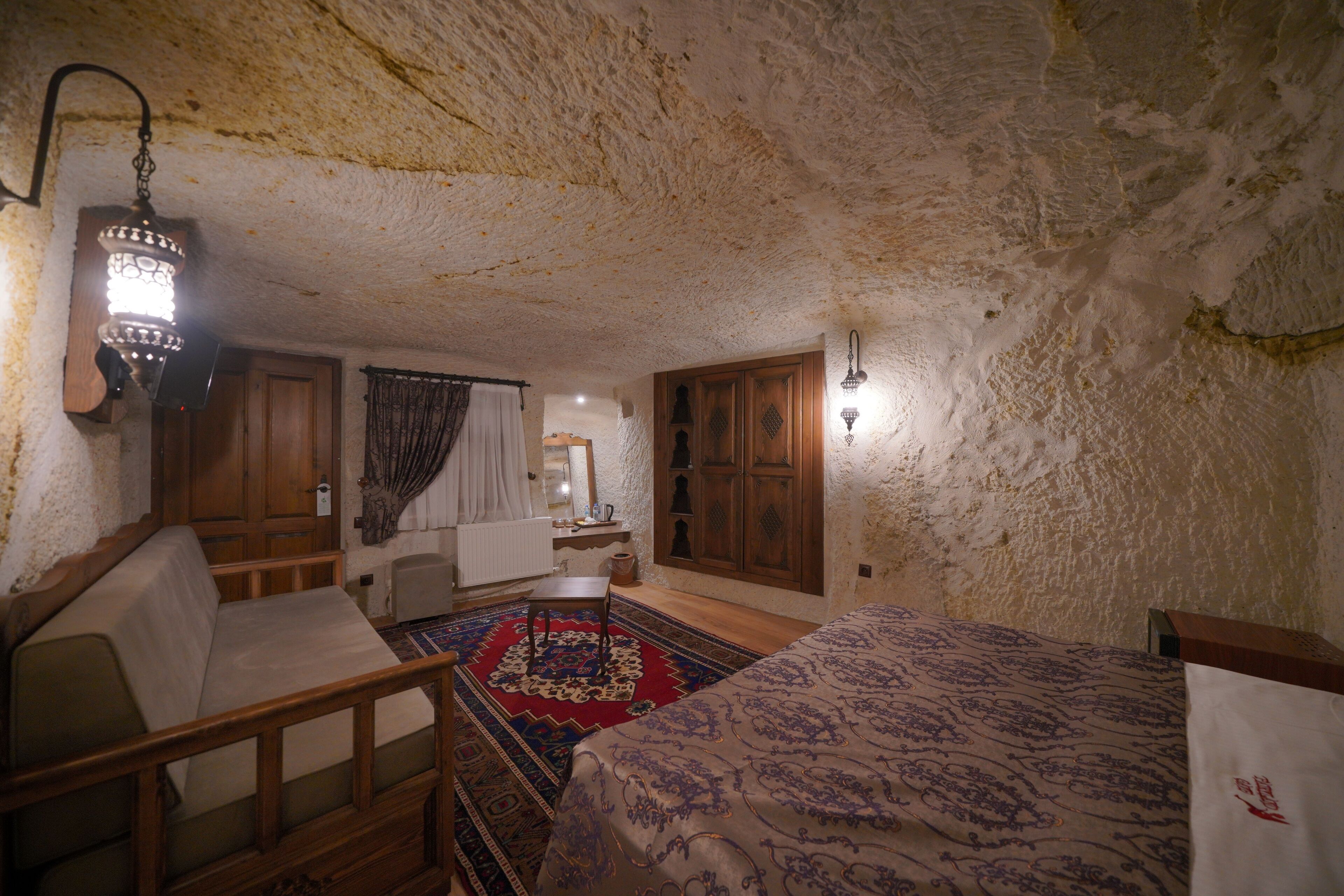 A cozy room with a wooden bed, a wooden chair, a small table, and a patterned rug.