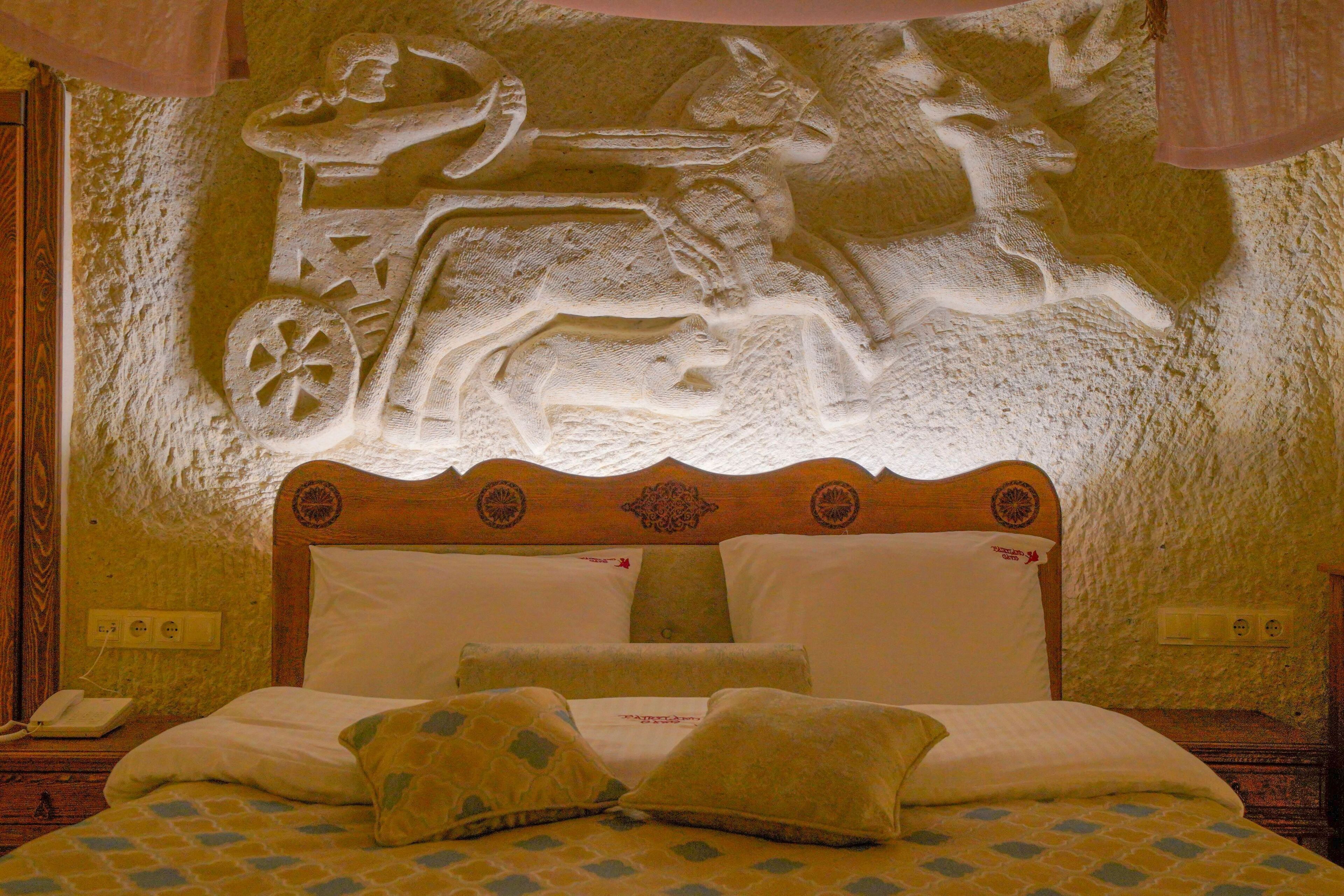 Un letto con una testiera decorata con un rilievo scolpito raffigurante un cavaliere a cavallo.