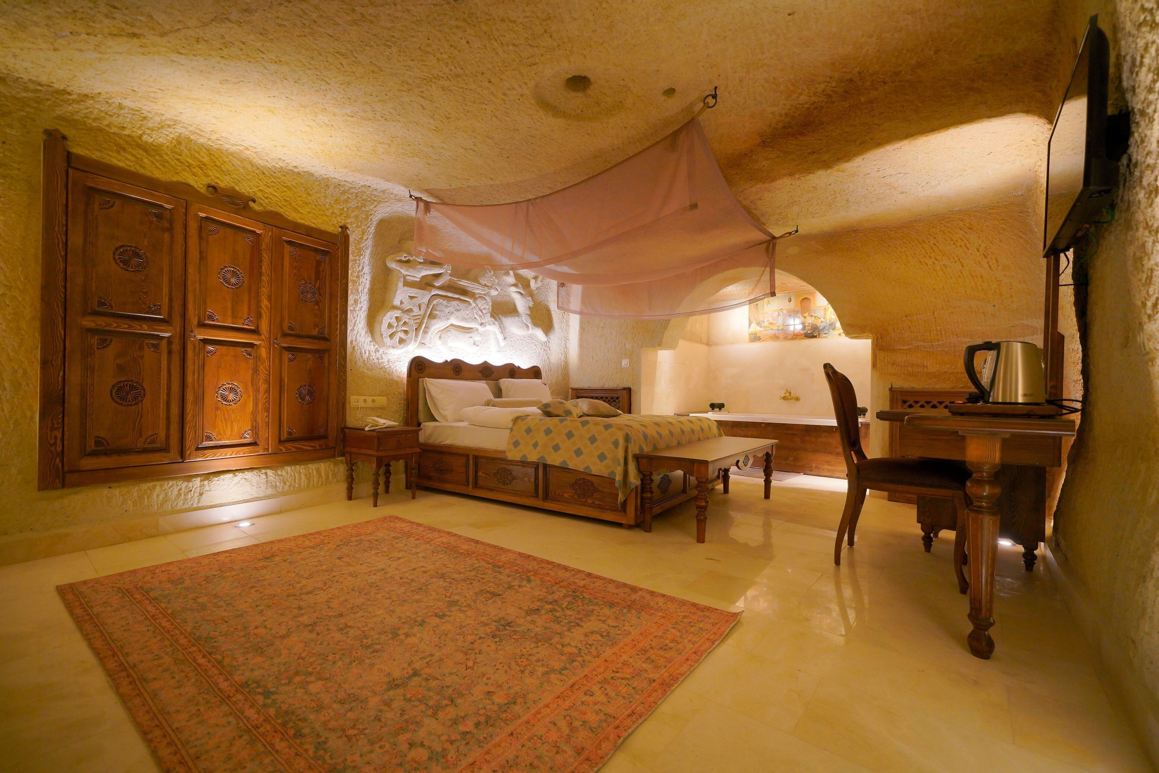 A bedroom with a bed, a desk, a chair, and a large rug.