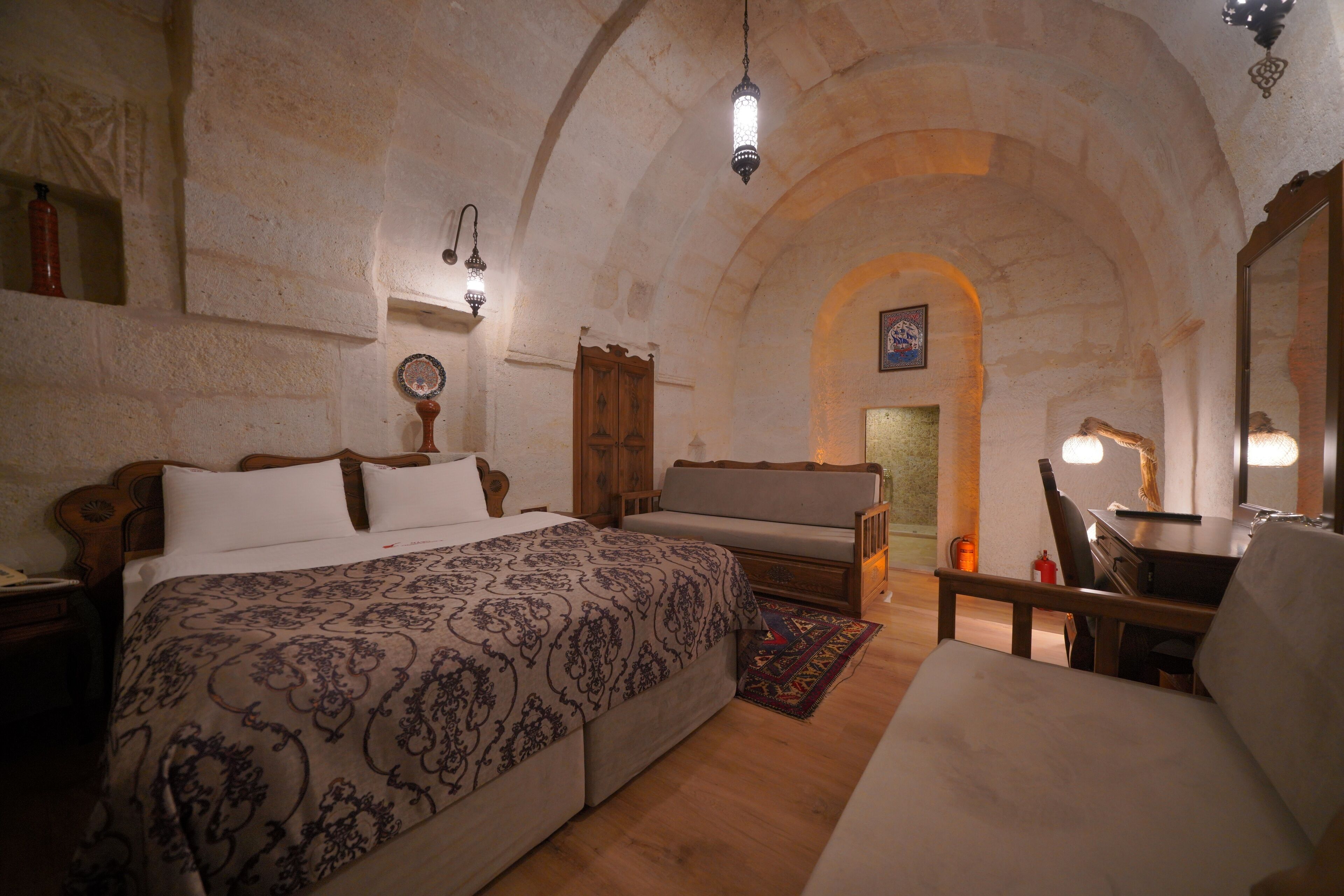 A cozy room with a large bed, a wooden bench, a desk, and a chair.