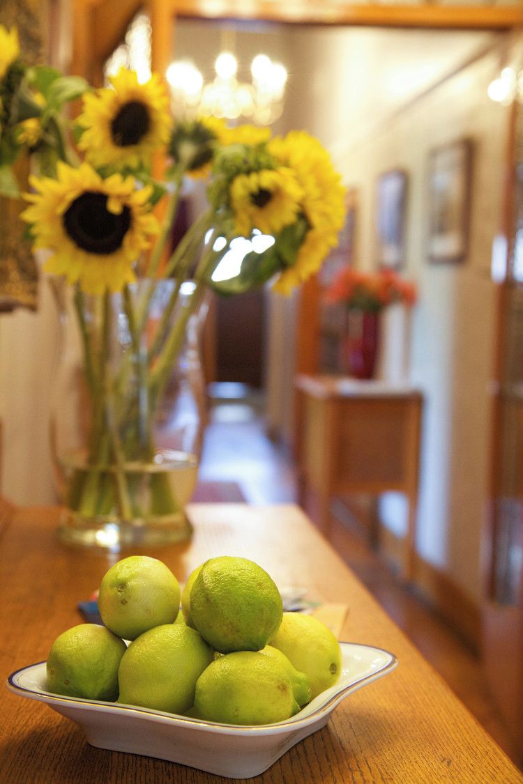Une table avec un bol de citrons et un vase de tournesols.