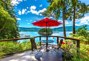 Une terrasse avec une table et des chaises, donnant sur un lac et un quai.